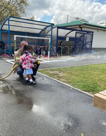 Nursey children taking turns using the fire hose